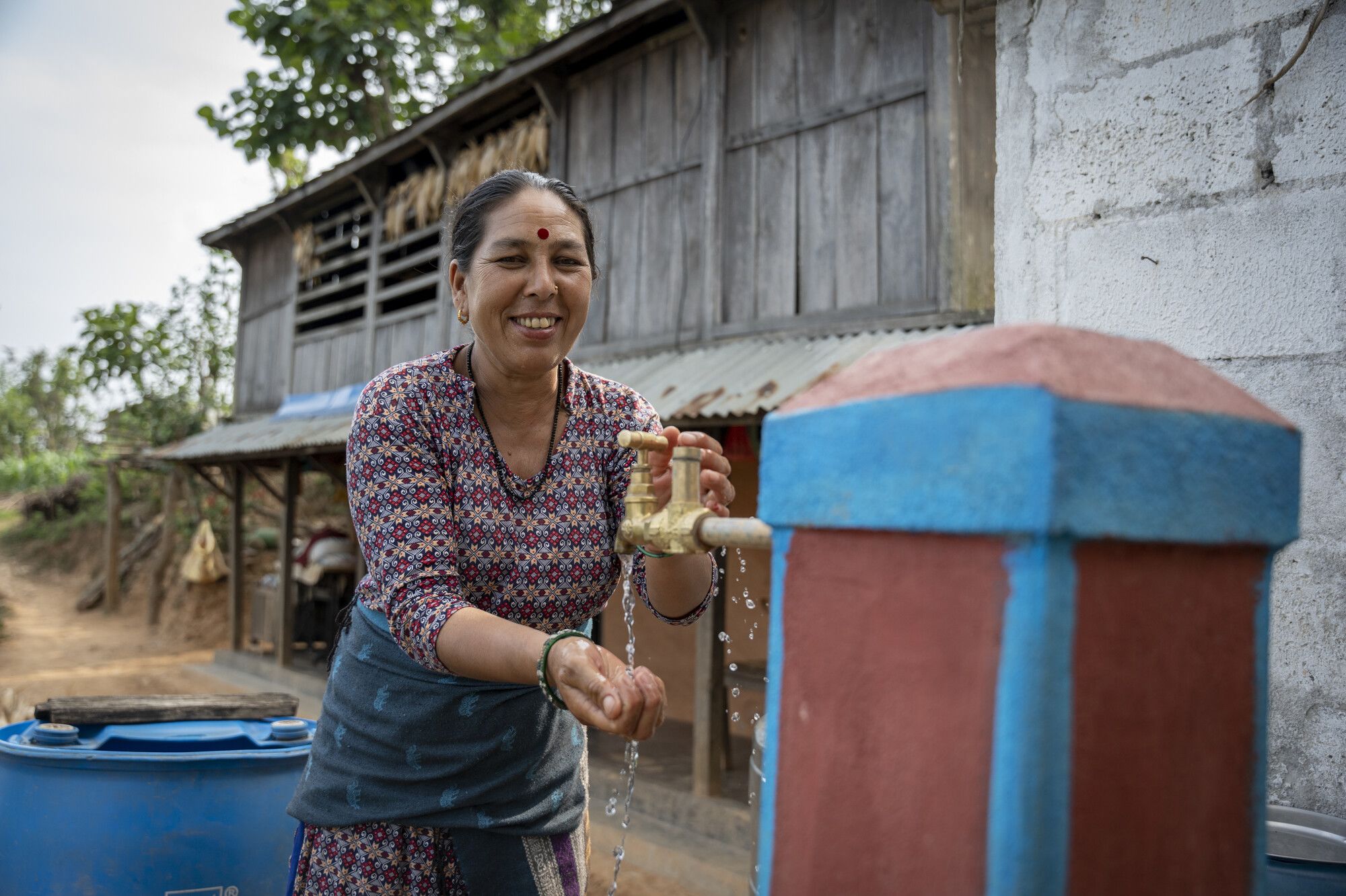 Pampha washes at the newly installed tap at her home, Dhading, Nepal. 